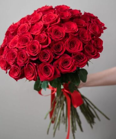 a hand holding a bouquet of red roses